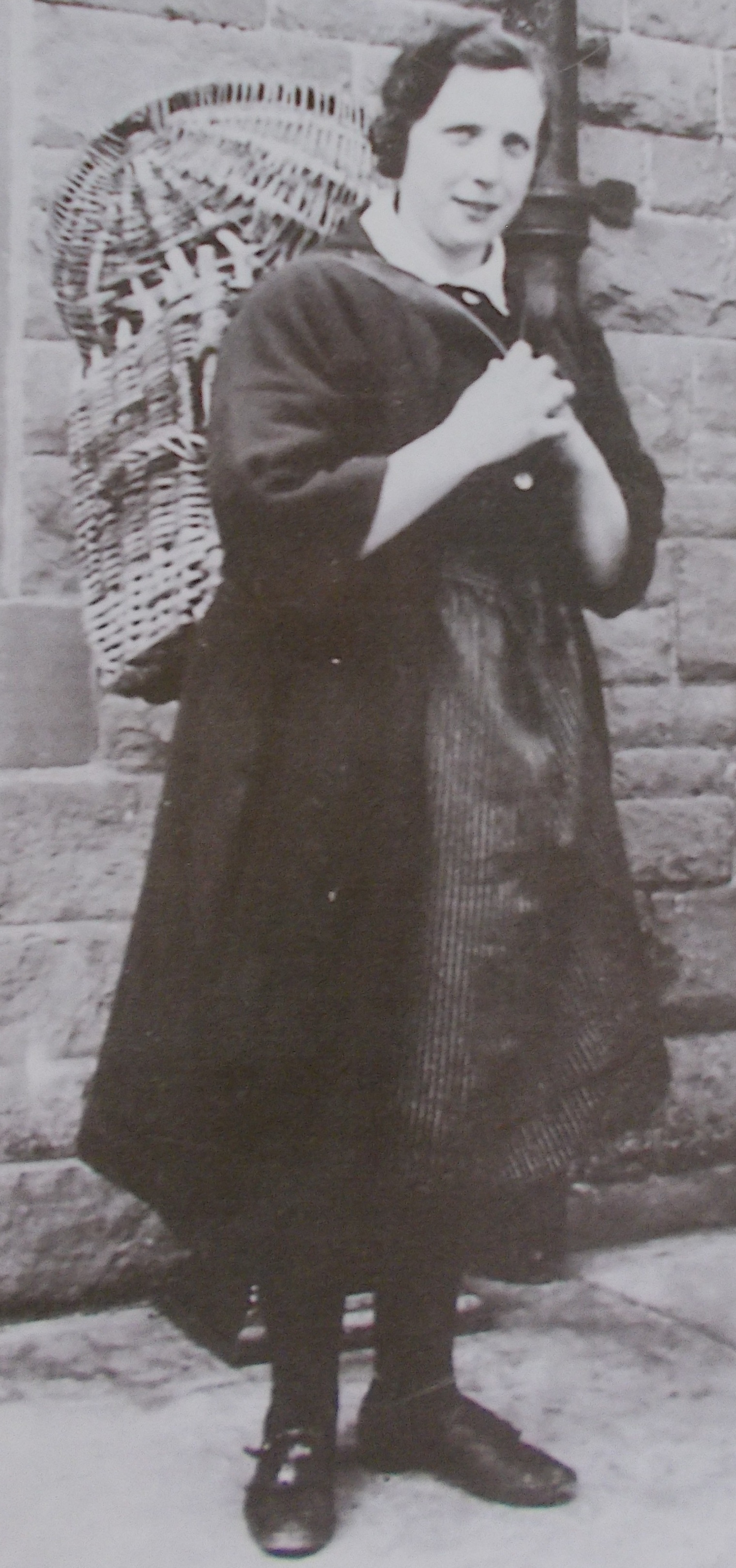 Historical photograph of a woman carrying a basket on her back